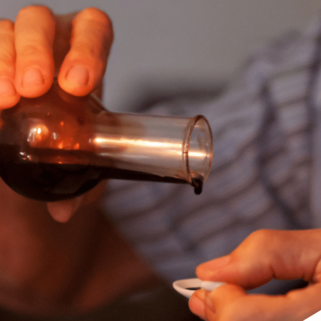 Dickflüssiger Aceto Balsamico wird auf einen Löffel getröpfelt- OLIPASO - Essig